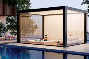 Modern glass pavilion by a poolside with a white sectional sofa and a hot tub inside, lanterns lit at dusk.